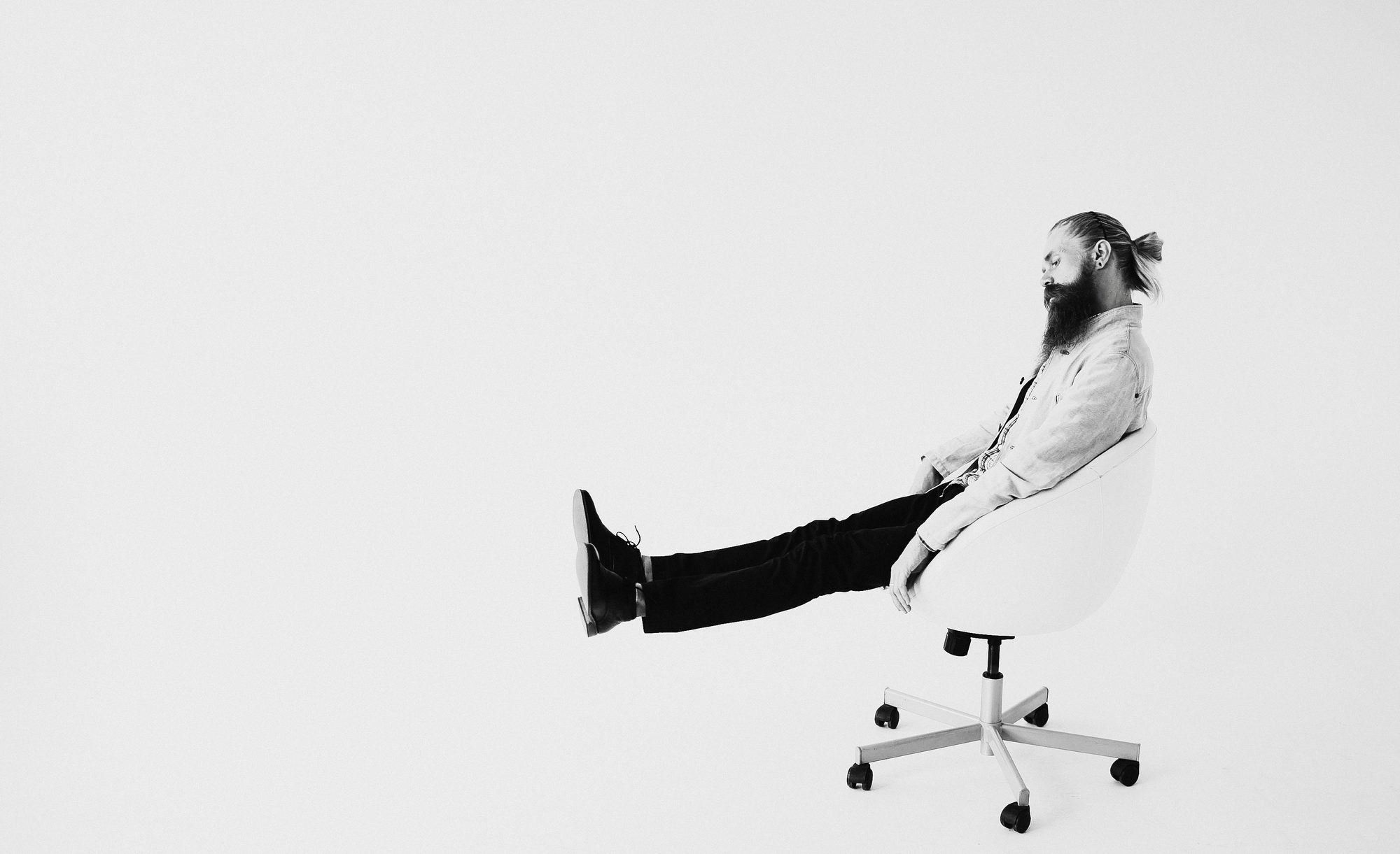 Creative professional reclining in a studio chair against a white backdrop